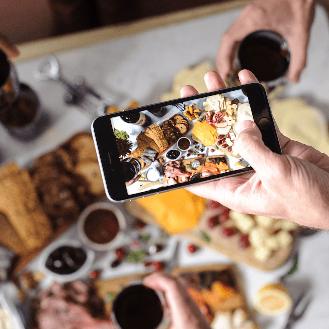 Taking a photo on a mobile phone of a food spread