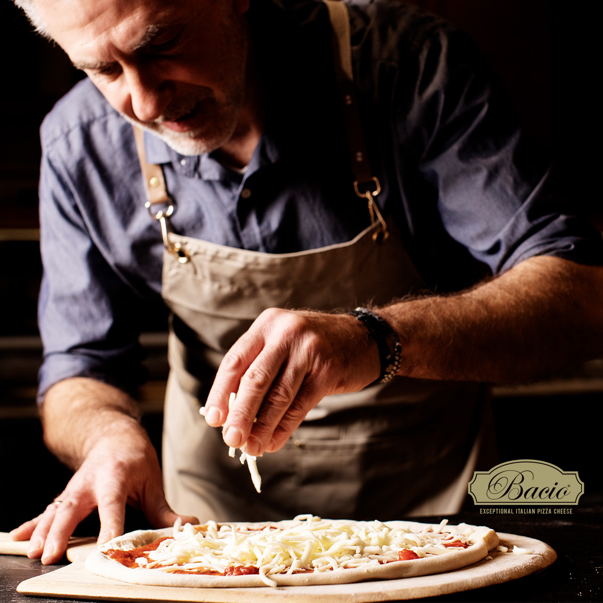 Bacio - Exceptional Italian Pizza Cheese, Man sprinkling cheese on pizza