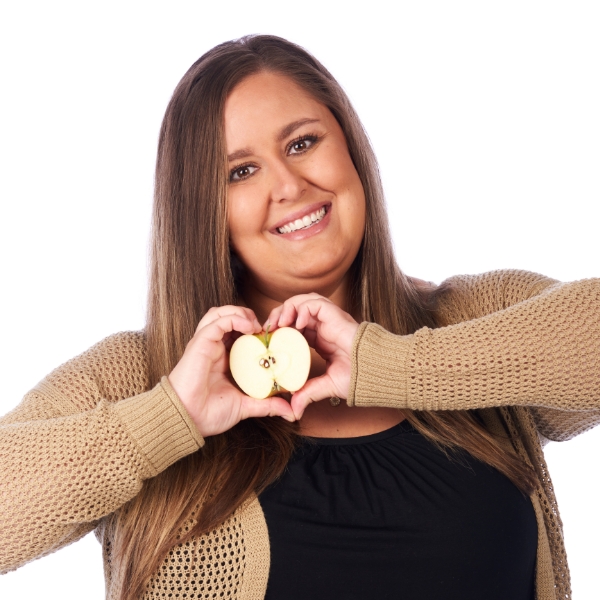 Melissa Stahn making a heart shape around half of an apple