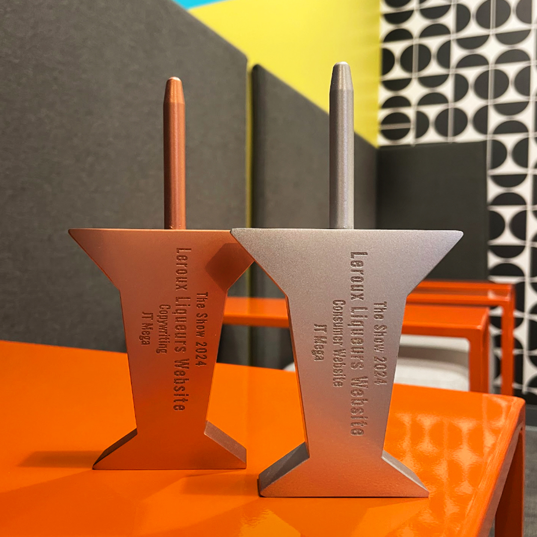 Bronze and silver pin from the AdFed Awards Show on an orange surface